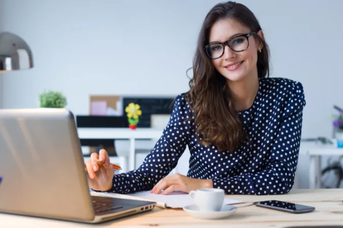 Mulher sorridente usando o laptop para organizar dados de forma produtiva.