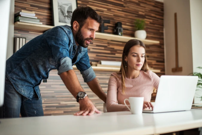 Duas pessoas analisando dados em um notebook para acompanhar horas de trabalho em um projeto.