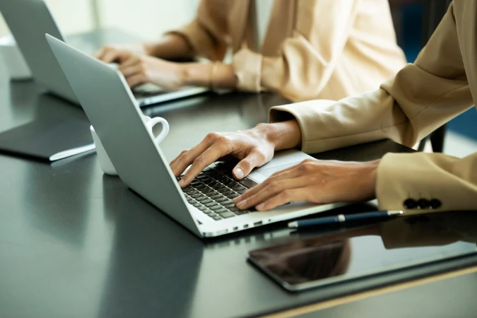 Profissional digitando em notebook para registrar horas de trabalho em sistema digital.