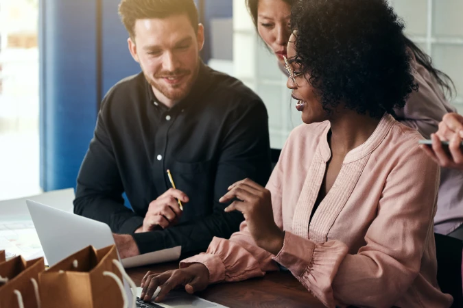 Grupo de profissionais analisando relatórios de horas e produtividade em um notebook.