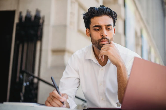 Homem analisando relatórios no notebook com apoio de um sistema de gestão financeira