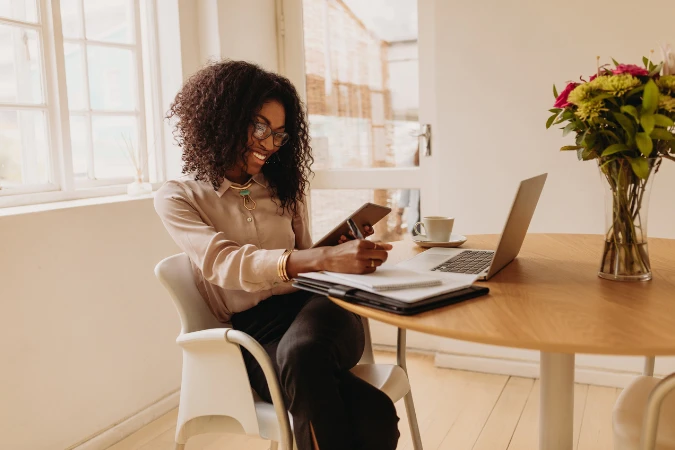 Profissional sorrindo enquanto organiza finanças no notebook com apoio de um sistema de gestão