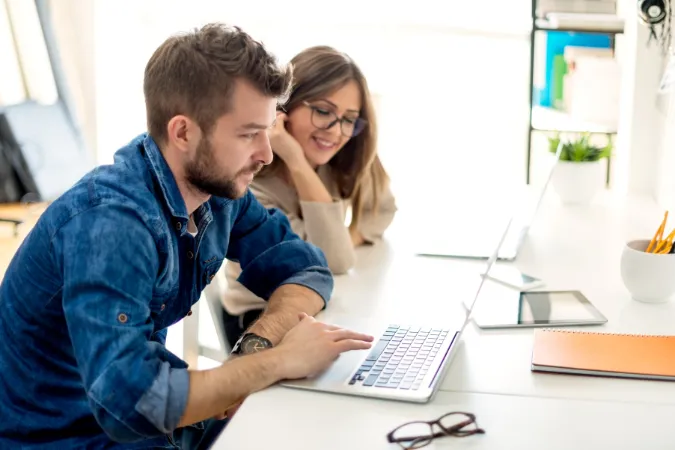 Dois profissionais analisando dados em laptop com sistema de gestão financeira online