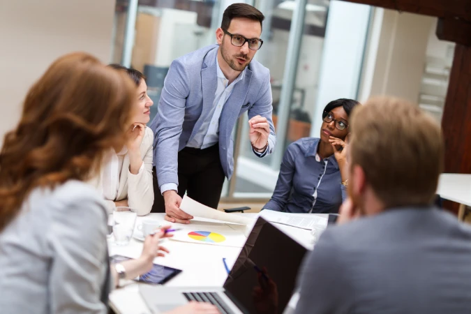 Gerente conduzindo reunião com equipe e analisando indicadores de desempenho
