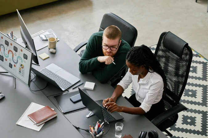 Profissionais analisando dados e relatórios em notebook durante reunião estratégica