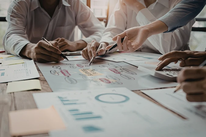 Equipe reunida analisando gráficos e metas estratégicas sobre mesa com relatórios financeiros.