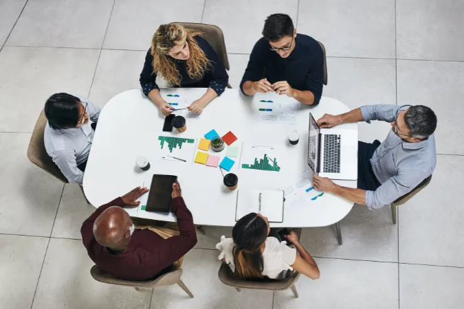 Equipe reunida em mesa de trabalho avaliando relatórios e indicadores financeiros