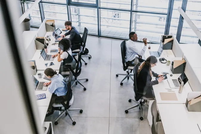 Profissionais trabalhando em computadores em um escritório colaborativo, utilizando sistemas digitais para organização de finanças.