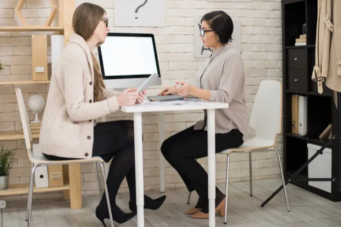 Líder dando feedback individual para colaboradora em reunião, promovendo inteligência emocional e flexibilidade.