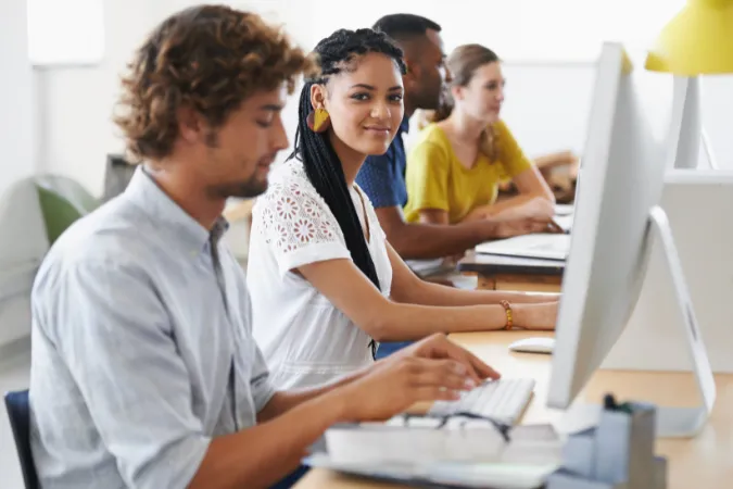 Profissionais em frente ao computador utilizando software de gestão para organizar tarefas no ambiente de trabalho.