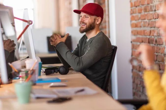 Profissional sorridente interagindo em escritório moderno, representando um ambiente de trabalho presencial produtivo.