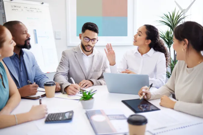 Profissionais de marketing em reunião estratégica utilizando software de gestão para alinhar tarefas e resultados.