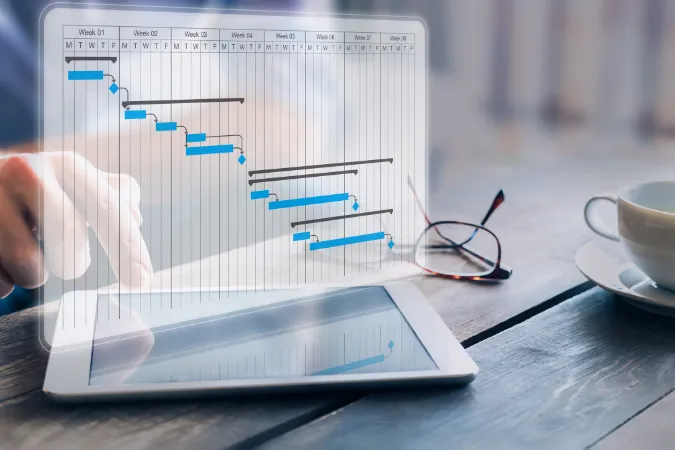 Pessoa usando tablet com sobreposição de gráfico de Gantt, destacando um cronograma de projeto detalhado com etapas e prazos.