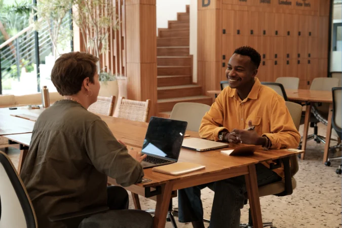 Equipe em reunião presencial usando notebooks para organizar projetos, tarefas e decisões em um ambiente colaborativo de trabalho.