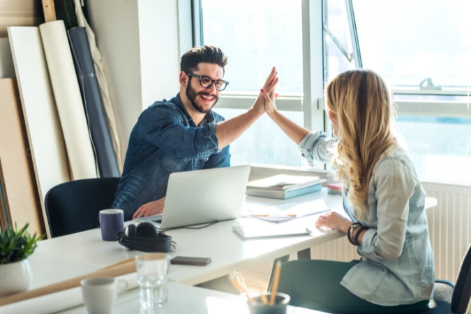 Colegas comemorando resultados positivos após análise de relatórios empresariais.
