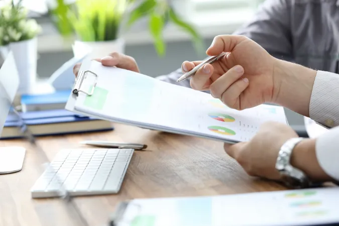Mãos analisando gráficos coloridos com indicadores de desempenho