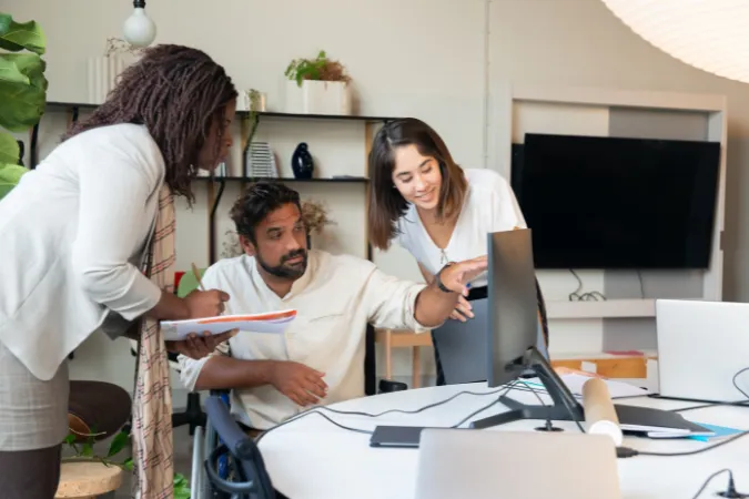 Equipe de consultoria reunida em frente ao computador discutindo planejamento estratégico de projetos com base no PMI