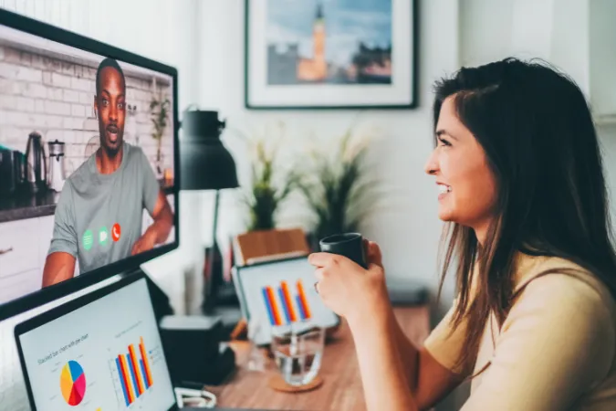 Gestora em videoconferência com dashboards e relatórios na tela