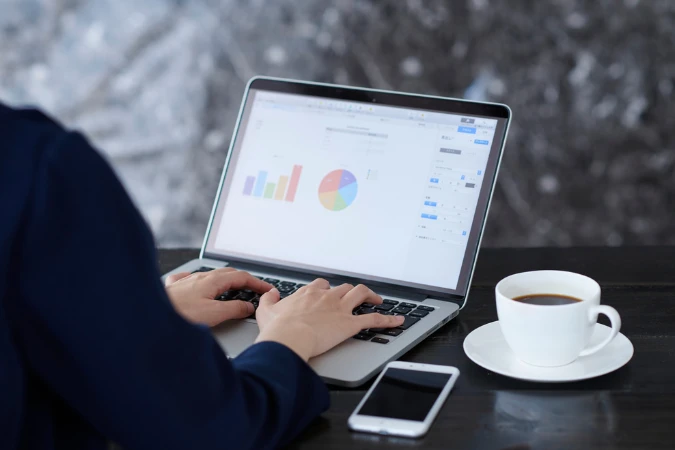 Profissional analisando gráficos e relatórios em um notebook para rastrear indicadores e detectar lacunas de performance.