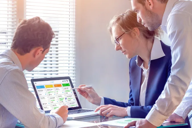 Equipe analisando quadro Kanban no computador para otimizar processos e evitar retrabalho