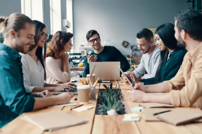 Grupo de colegas sorrindo em reunião de trabalho em ambiente descontraído