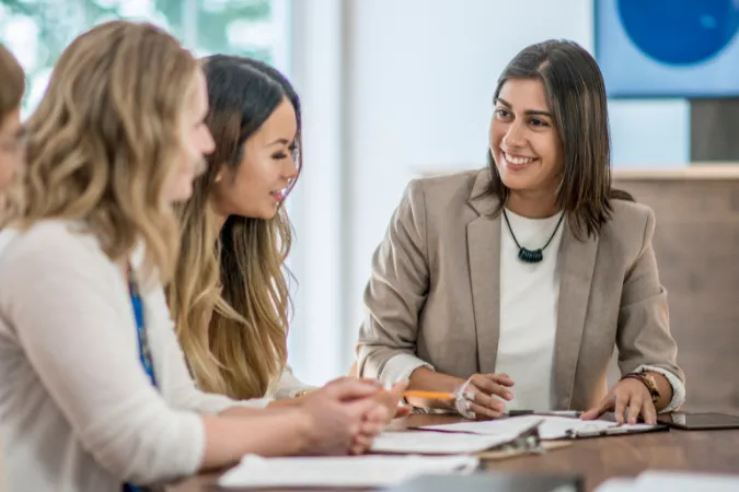 Equipe reunida em reunião sorridente, aplicando o Feedback Canvas para troca de percepções