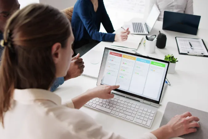 Profissional analisando um painel digital em computador com fluxo de tarefas no estilo Kanban, representando software de gestão aplicado ao Water Scrum Fall.