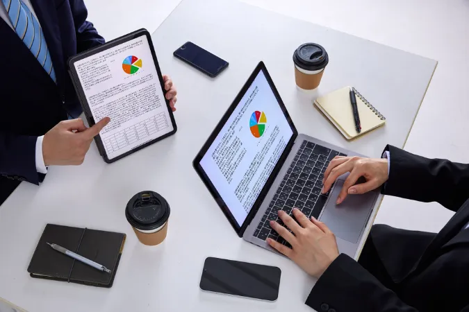 Profissionais utilizando softwares de gestão para monitorar orçamento em dispositivos digitais