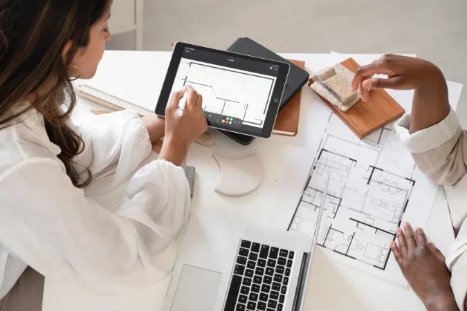 Arquitetos revisando planta baixa digital em tablet para ajustes durante a fase de anteprojeto.