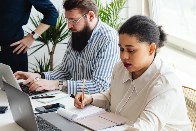 Profissionais utilizando software de gestão em notebooks para organizar tarefas e acompanhar projetos no trabalho.