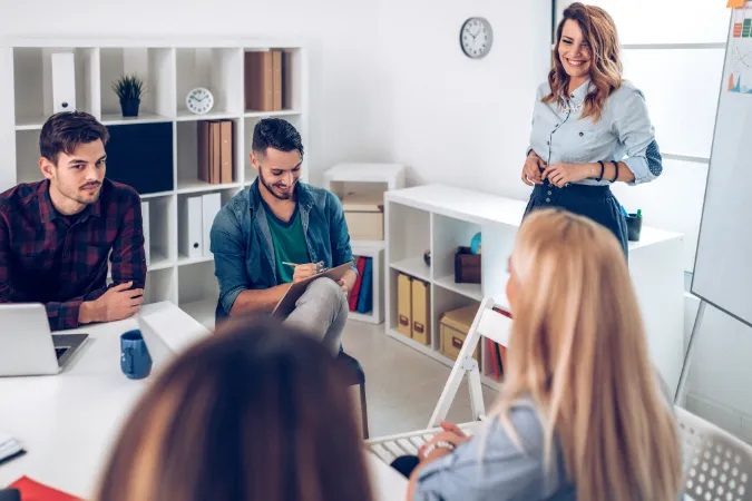 Equipe de colaboradores em reunião de trabalho organizada com a gestora conduzindo a discussão.