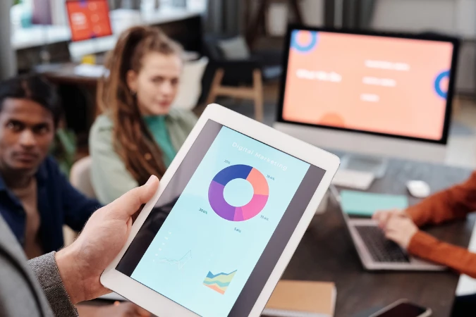 Equipe analisando dados e indicadores em tablet durante reunião estratégica, refletindo práticas de transformação ágil