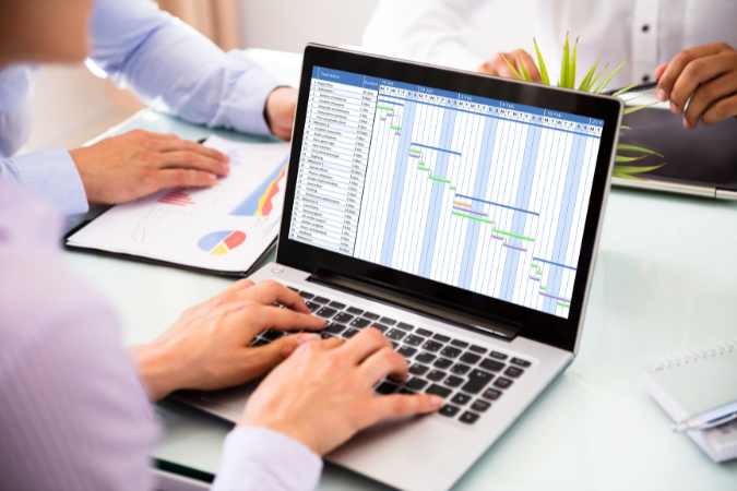 Pessoa analisando gráfico de Gantt com cronograma detalhado em um notebook