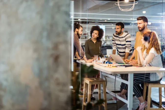 Grupo de profissionais discutindo juntos em uma reunião para integrar a técnica dos 5 Porquês na cultura da empresa.