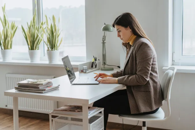 Mulher analisando causas raiz de problemas em um software de gestão no notebook com a técnica dos 5 Porquês.