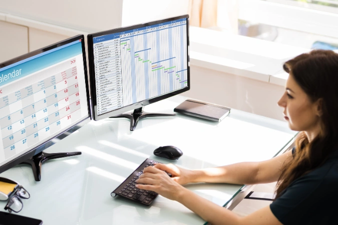 Profissional acompanhando o Diagrama de Gantt em dois monitores para controlar prazos, etapas e produtividade da equipe