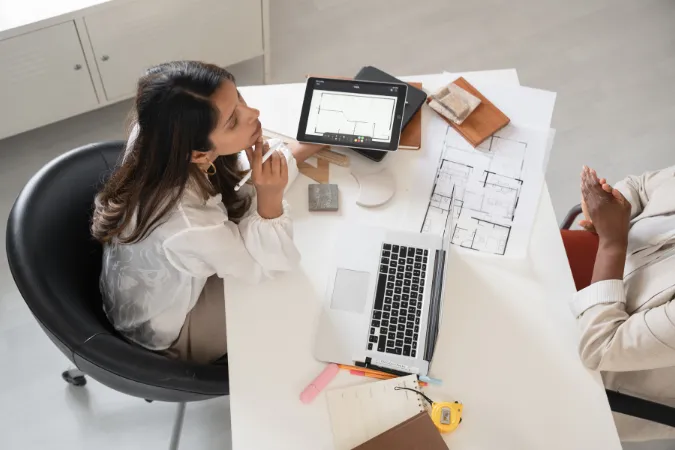 Arquitetas analisando plantas digitais em software de gestão para organizar projetos com eficiência