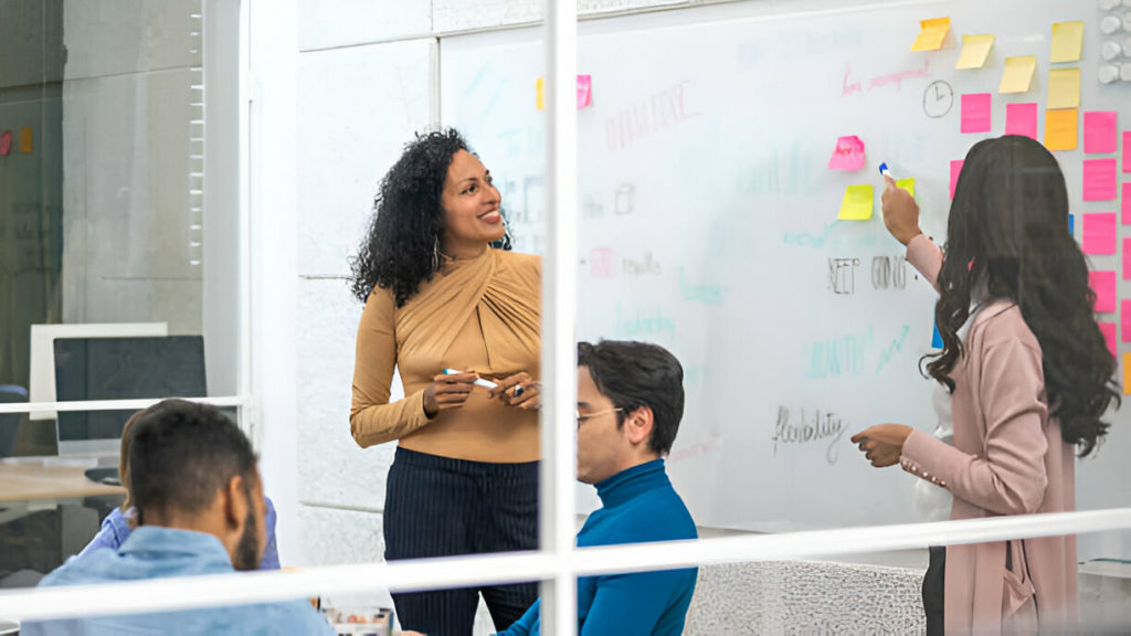 Gerentes de projeto sorridentes explicando a técnica de brainstorming para colegas em reunião de escritório