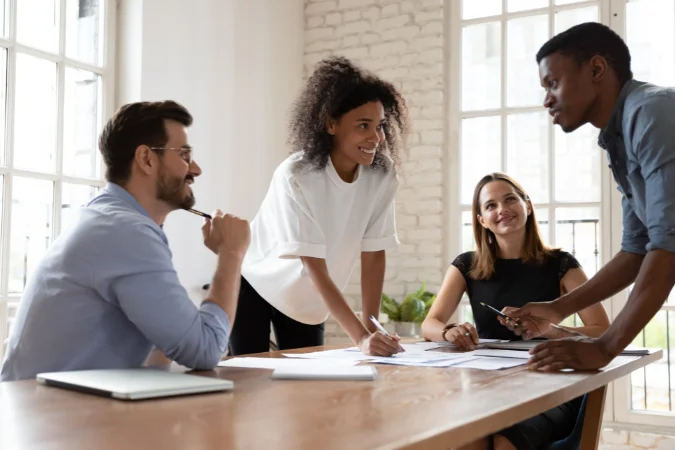Gestor conduz reunião com a equipe em torno de uma mesa, aplicando soft skills para melhorar comunicação e colaboração nas tarefas.