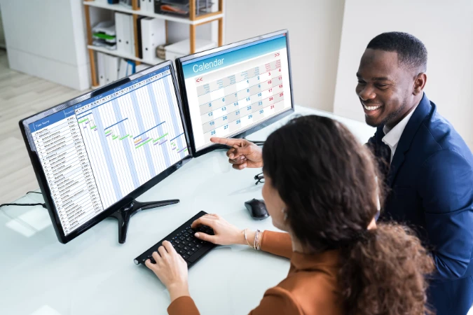 Profissional observando um Diagrama de Gantt com tarefas organizadas por fases em um monitor de computador.