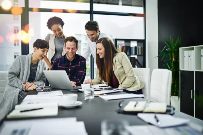 Equipe diversa colaborando em torno de um notebook, ilustrando a importância das soft skills para um gestor de tarefas.