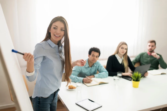 Gestora apresentando plano estratégico em reunião com equipe, utilizando quadro e relatórios.