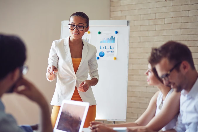 Gestora apresentando gráficos e indicadores de desempenho de projetos em uma reunião de resultados.