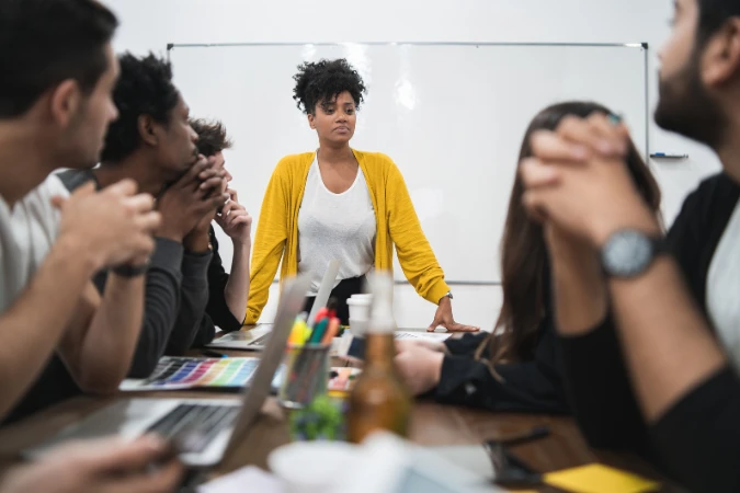 Líder de projeto apresentando plano de ação a uma equipe multidisciplinar em reunião.