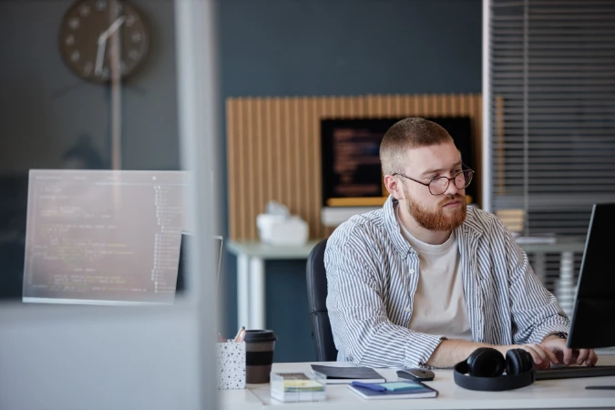 Profissional monitorando tarefas no computador para garantir que o cronograma inteligente reflita o andamento real.