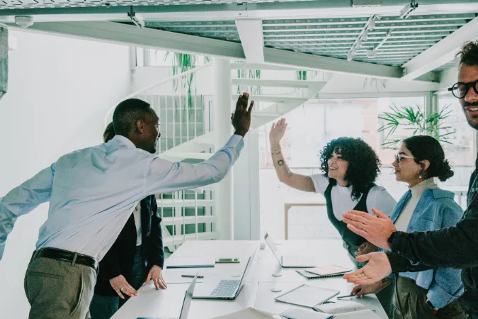 Profissionais em reunião de projetos comemorando sucesso após aplicar práticas do PMBOK com apoio de software de gestão