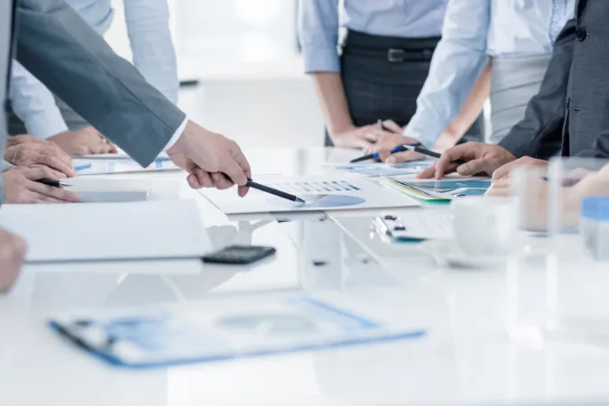 Equipe de gestão de projetos avaliando gráficos e indicadores de desempenho em mesa de reunião