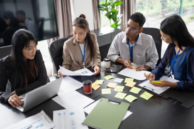 Equipe revisando tarefas e prioridades em um cronograma adaptável com anotações e documentos na mesa.