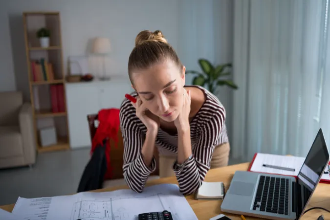 Engenheira em frente ao computador olhando pranchas, representando a ociosidade em equipes de engenharia e arquitetura causada por falhas de comunicação e atrasos no cronograma.