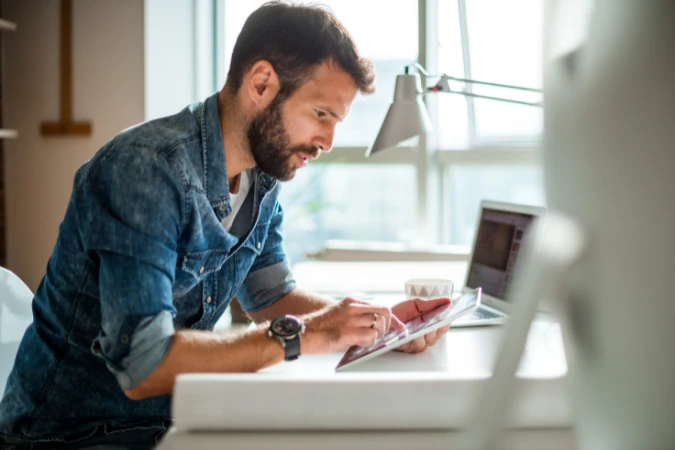 Profissional analisando tarefas em um tablet para organizar projetos de forma produtiva.